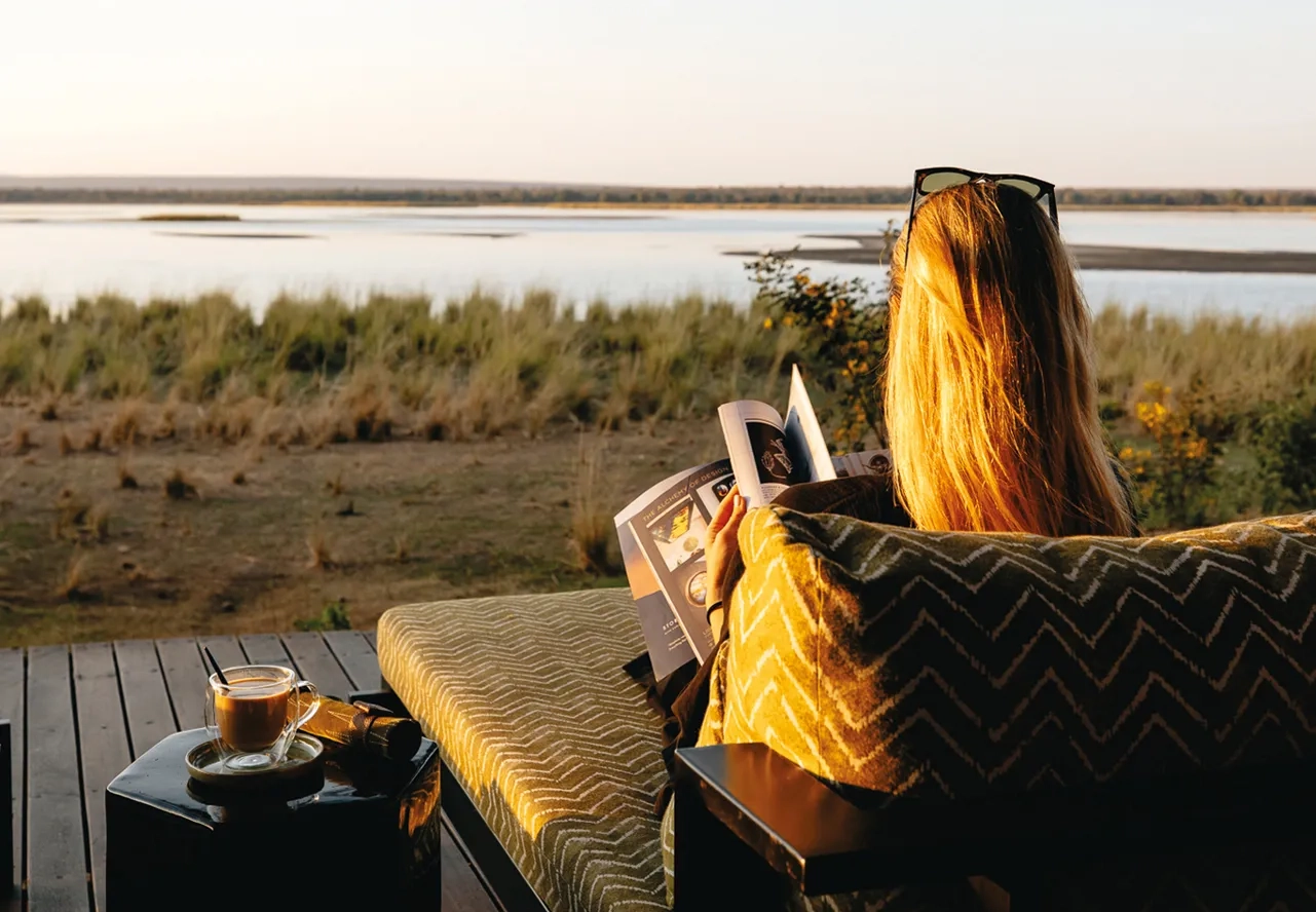 A woman reading on a riverside terrace at Lolebezi Zambia 