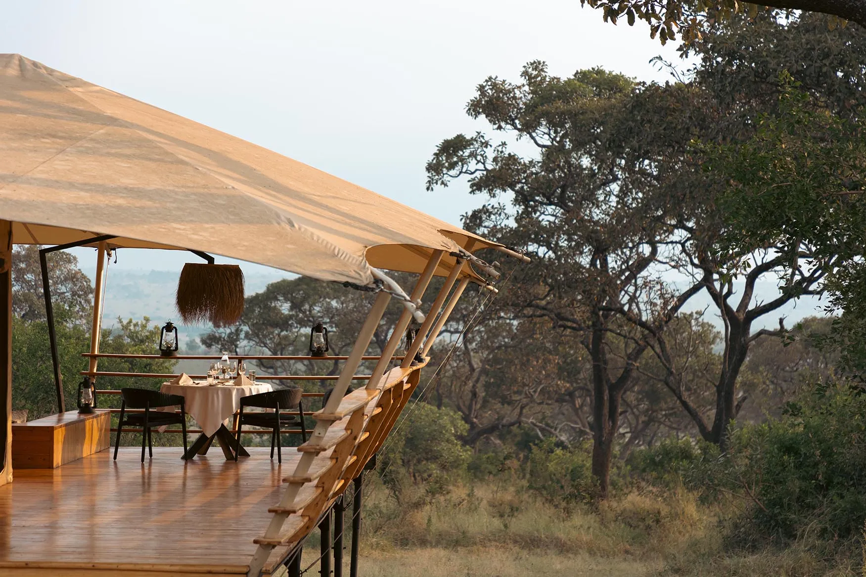 Africa, Tanzania, Serengeti Bushtops, dining table set for two in raised luxury tent looking out to the bushlands