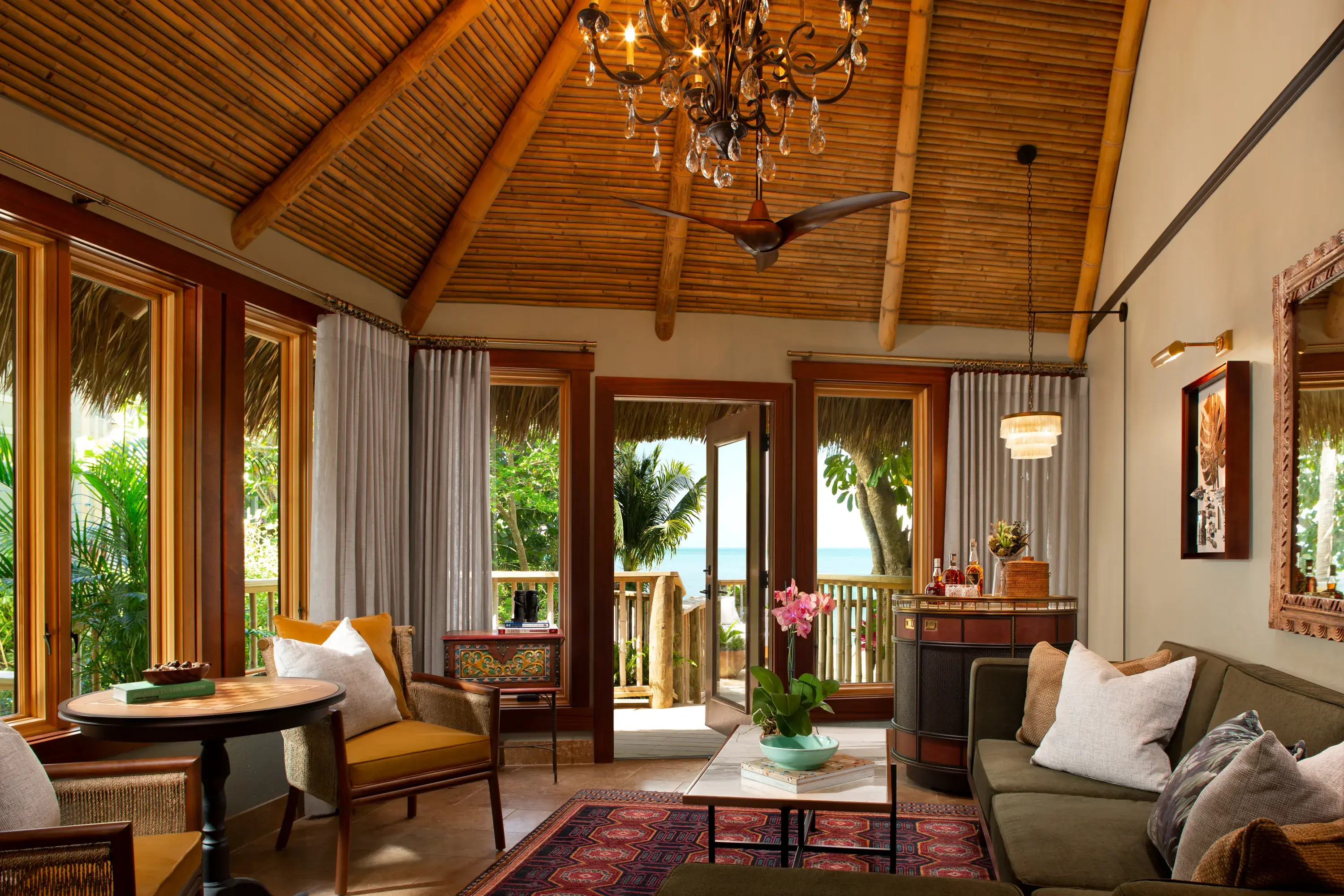 Elegant Romance Suite at Little Palm Island Resort in Florida featuring vaulted bamboo ceiling, chandelier, and ocean-view terrace.