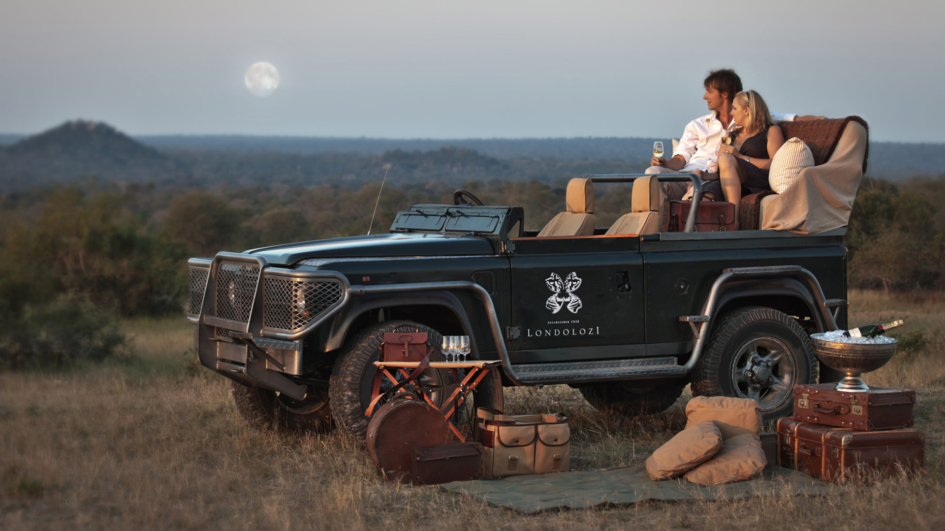 A couple in a safari jeep drinking wine at Londolozi