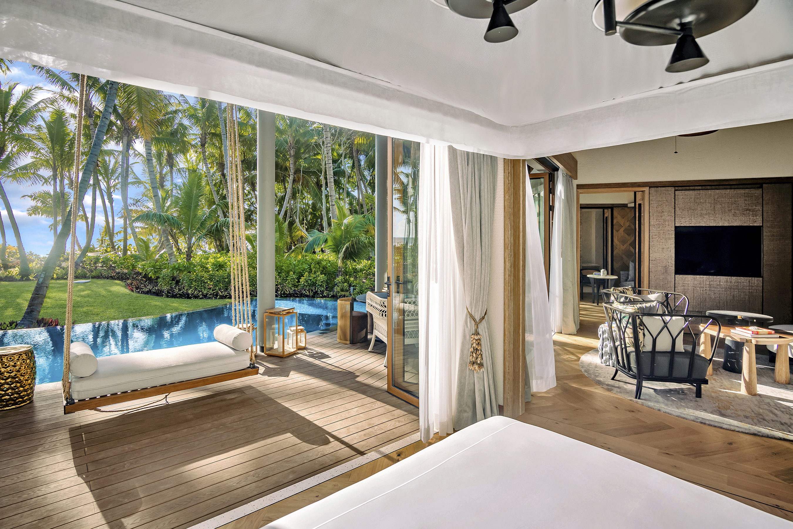 Multiple spaces within a pool villa including the bedroom, lounge area and terrace with hanging chair