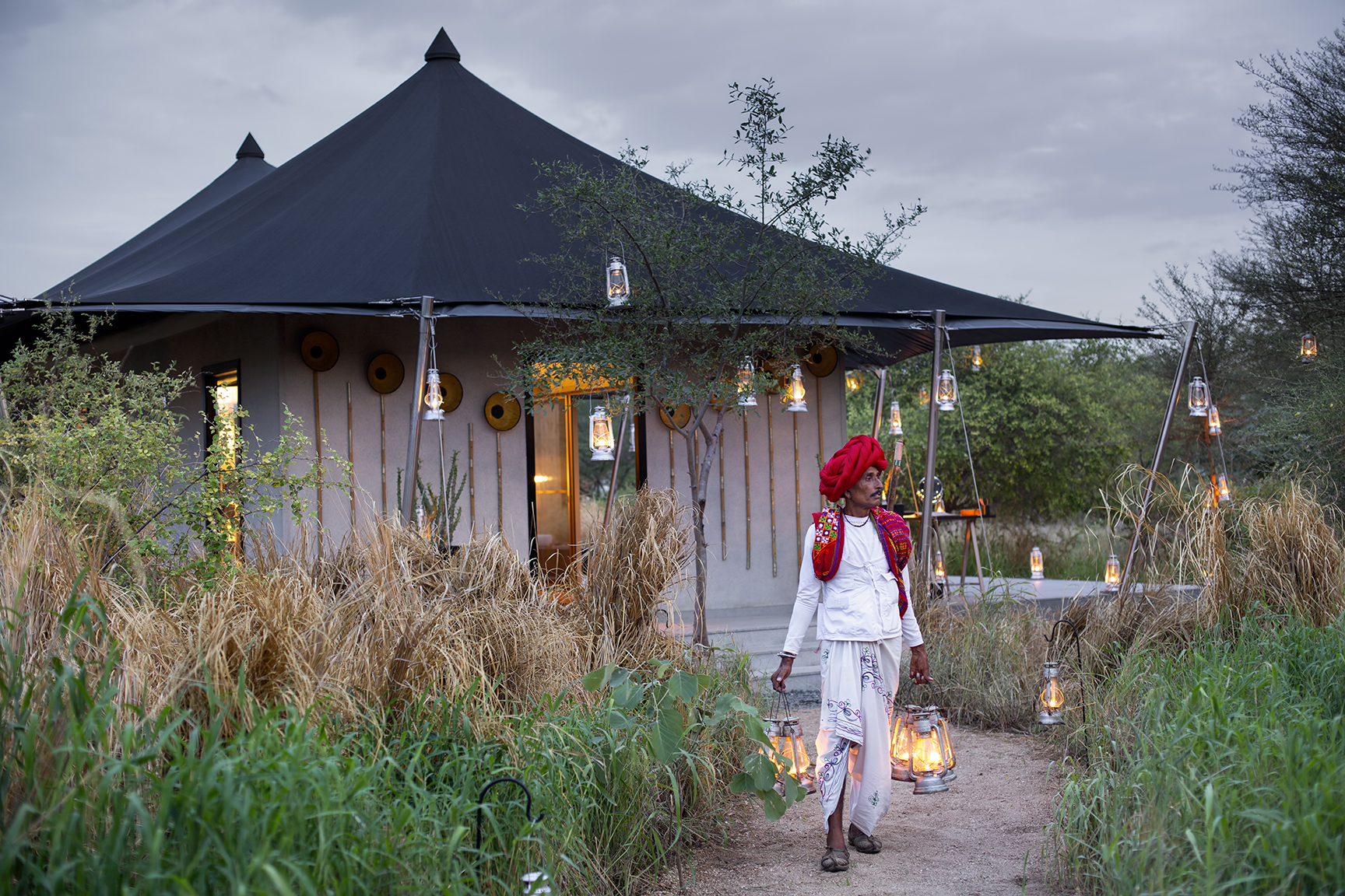 Asia, India, Sujan Jawai, man walking away from tented accommodation lit by torches