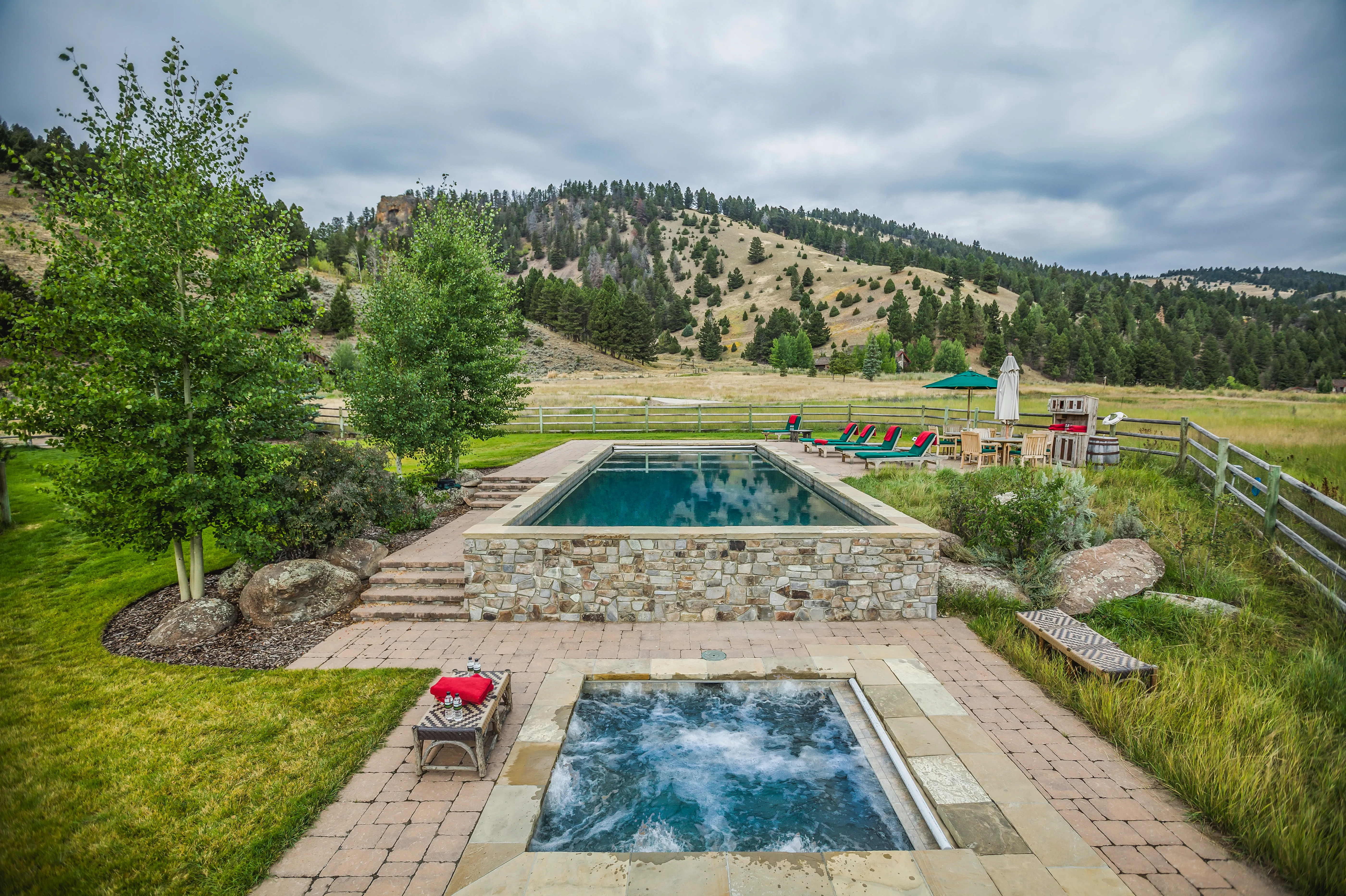Outdoor pool and hot tub at The Ranch at Rock Creek in Montana surrounded by stone patios and grassland