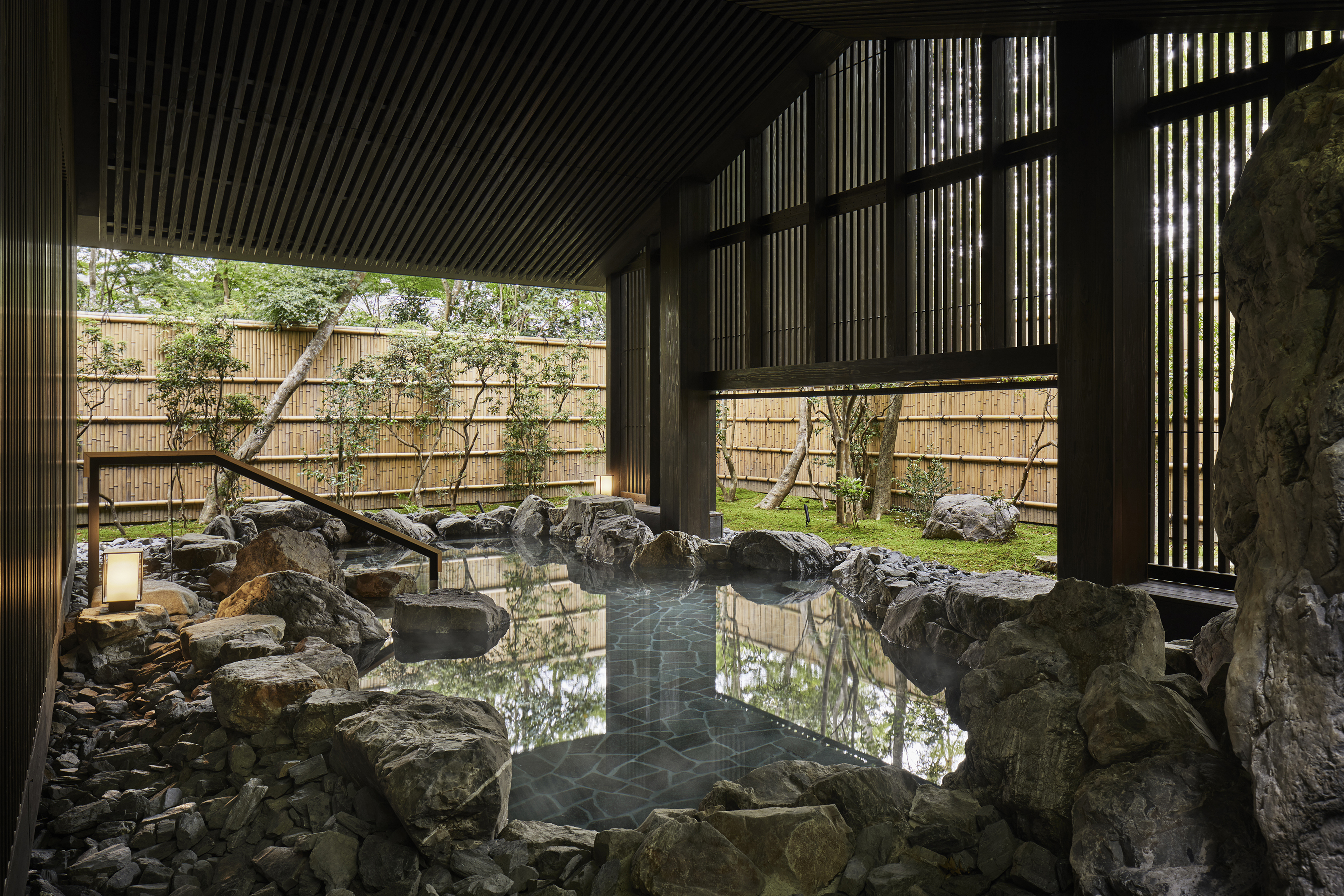A traditional stone onsen beneath a wood panelled roof 