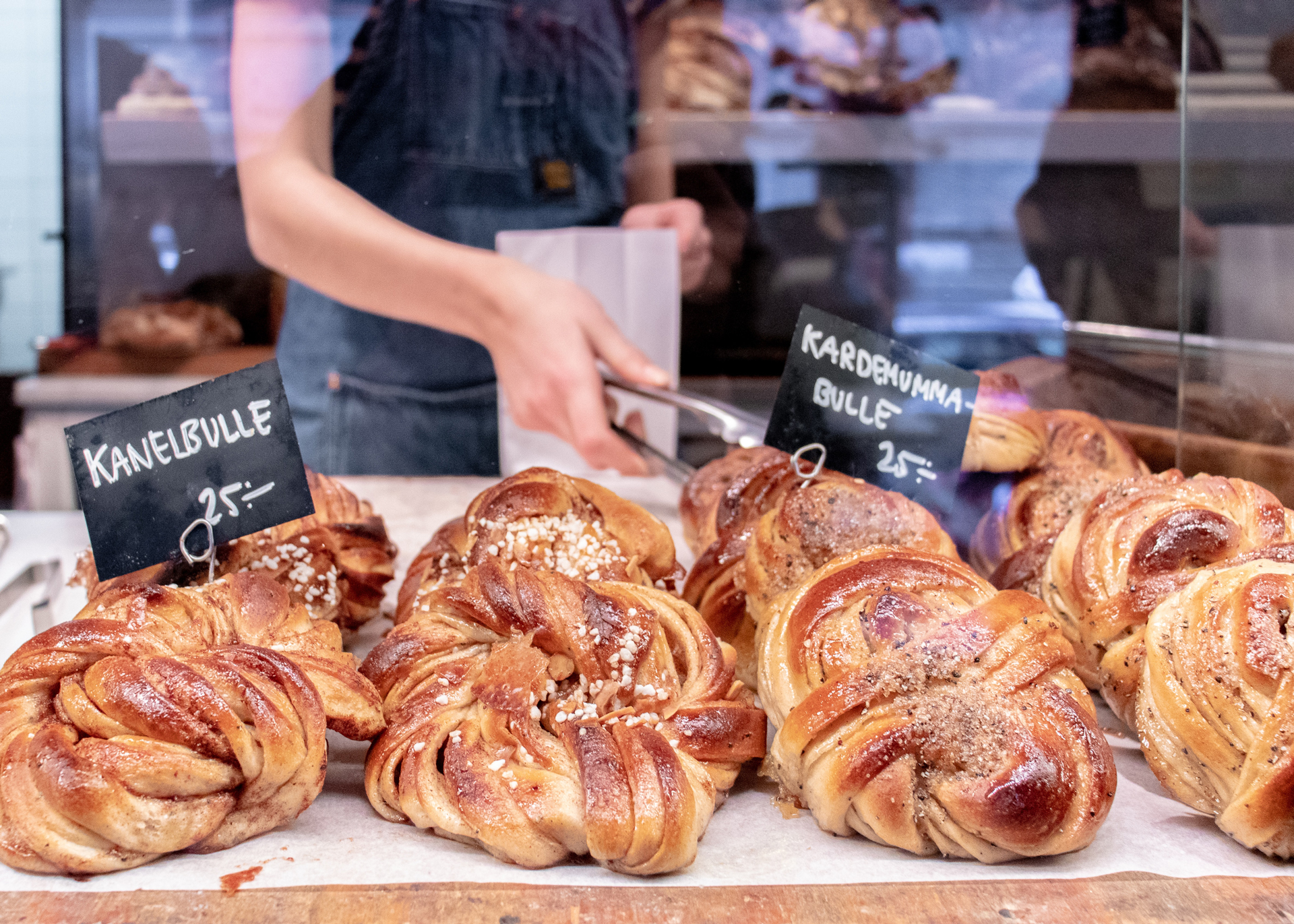 Baked bread in a bakery display with the labels Kanelbulle and Kardemumma bulle