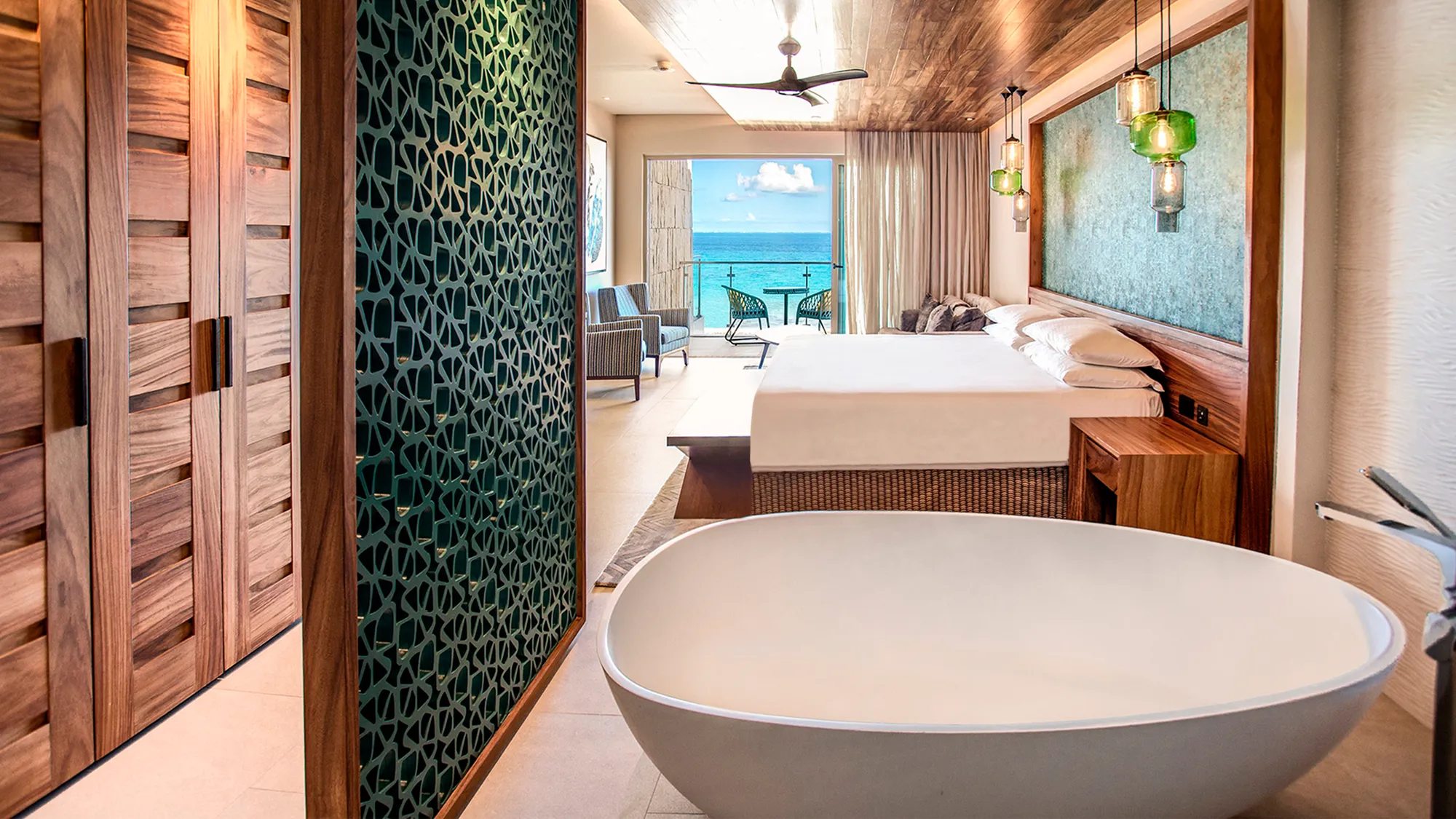 Contemporary ocean‑view suite with freestanding bath and balcony overlooking the sea.