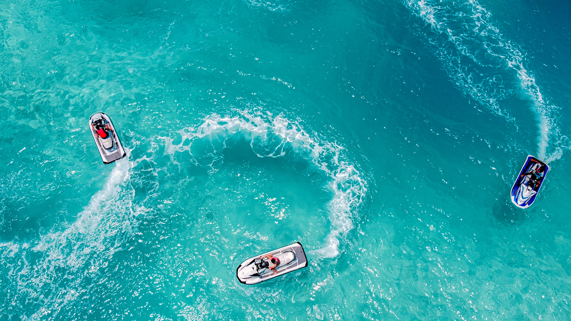 an ariel image of three people riding jet skis 