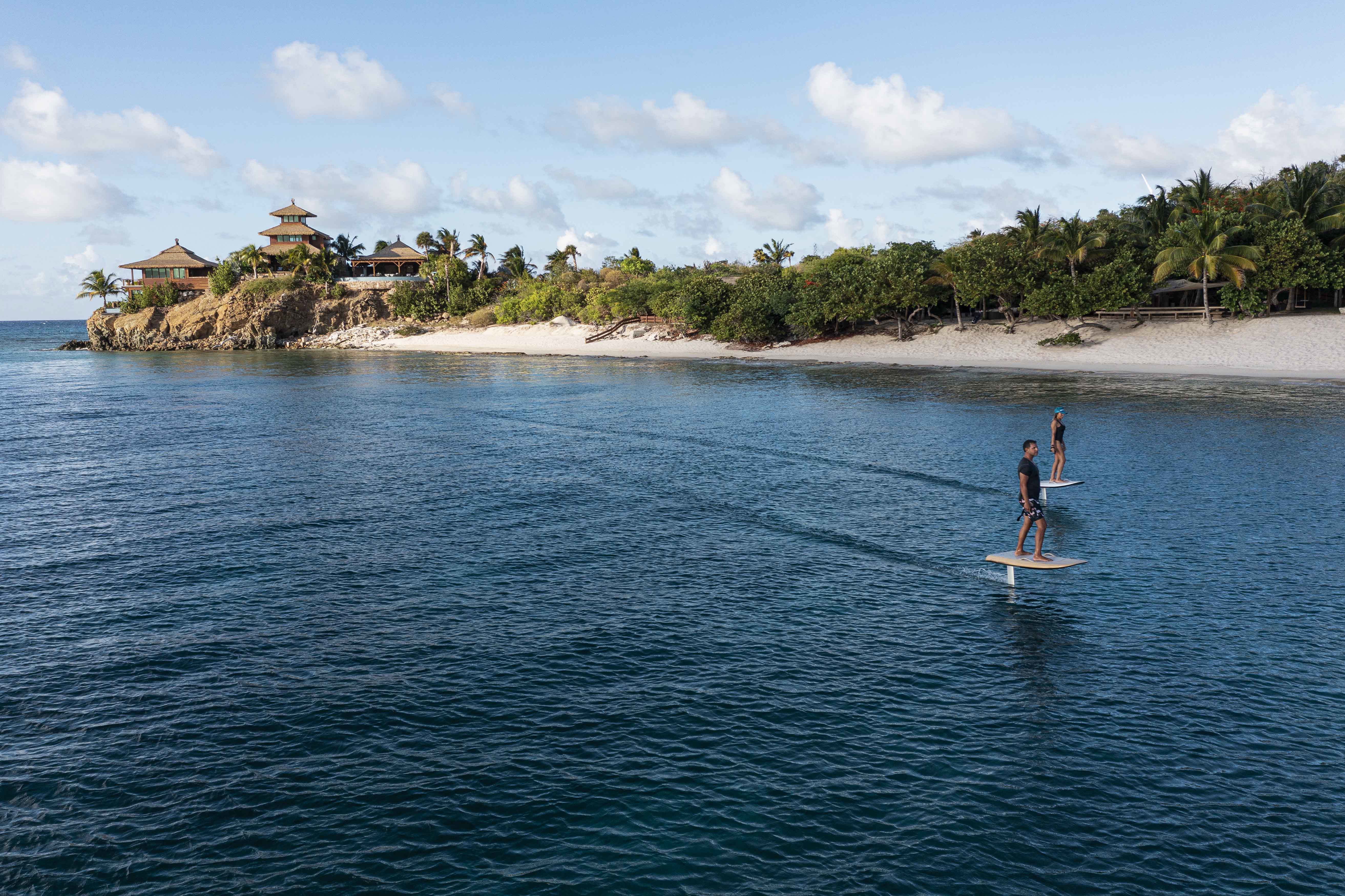 A couple efoiling across a calm ocean with an island in the background