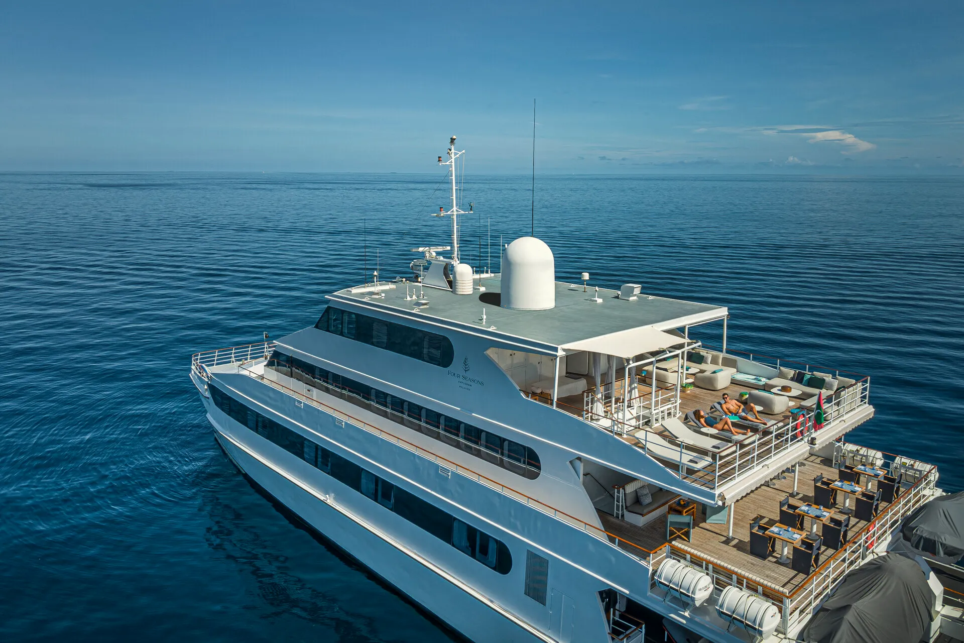 Four Seasons Explorer Palau boat anchored in a calm sea with two people sun bathing on the top deck