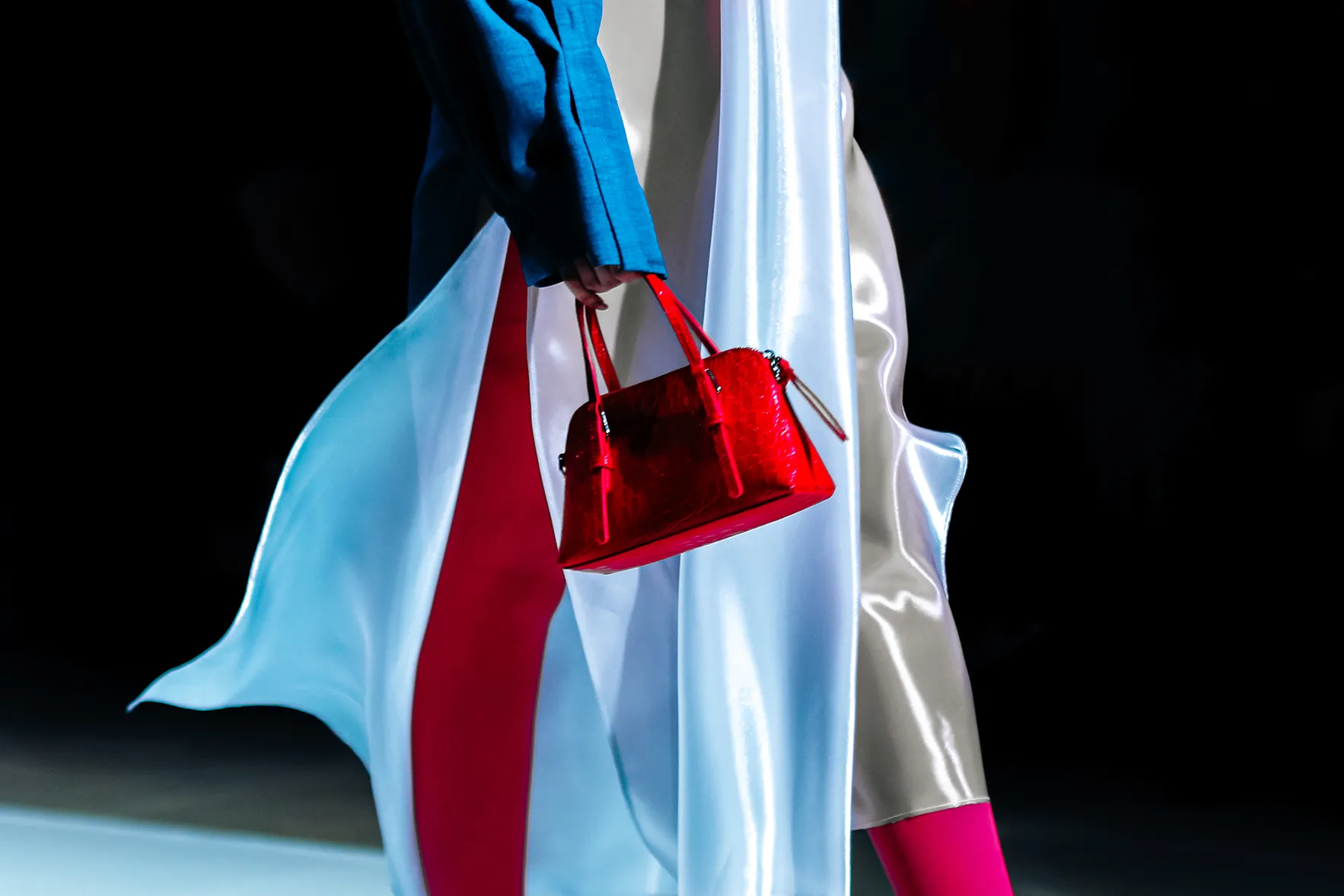A close up image of a red bacg held by a model walking the runway at Milan Fashion Week 