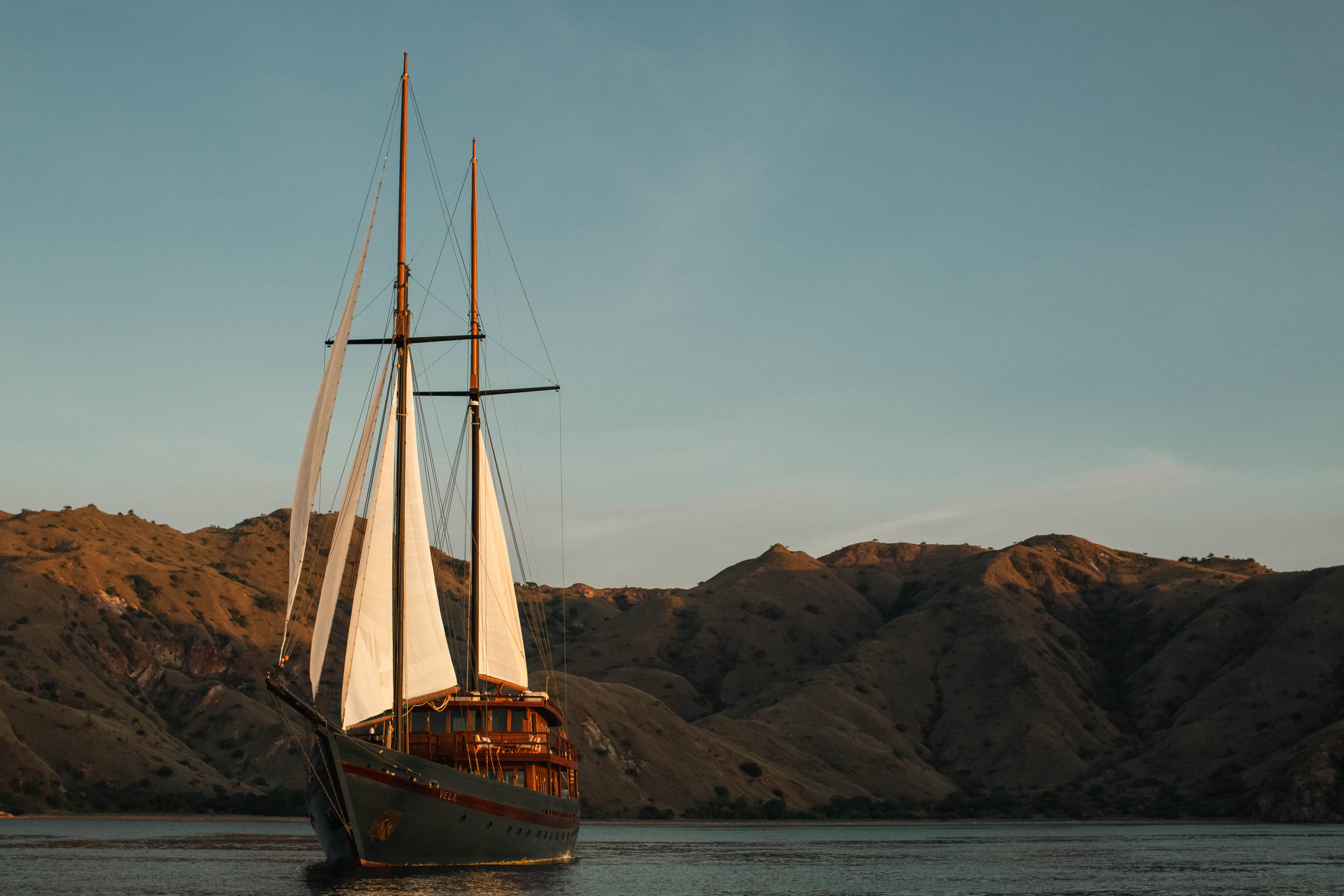 A front on view of the Vela yacht with an island in the background