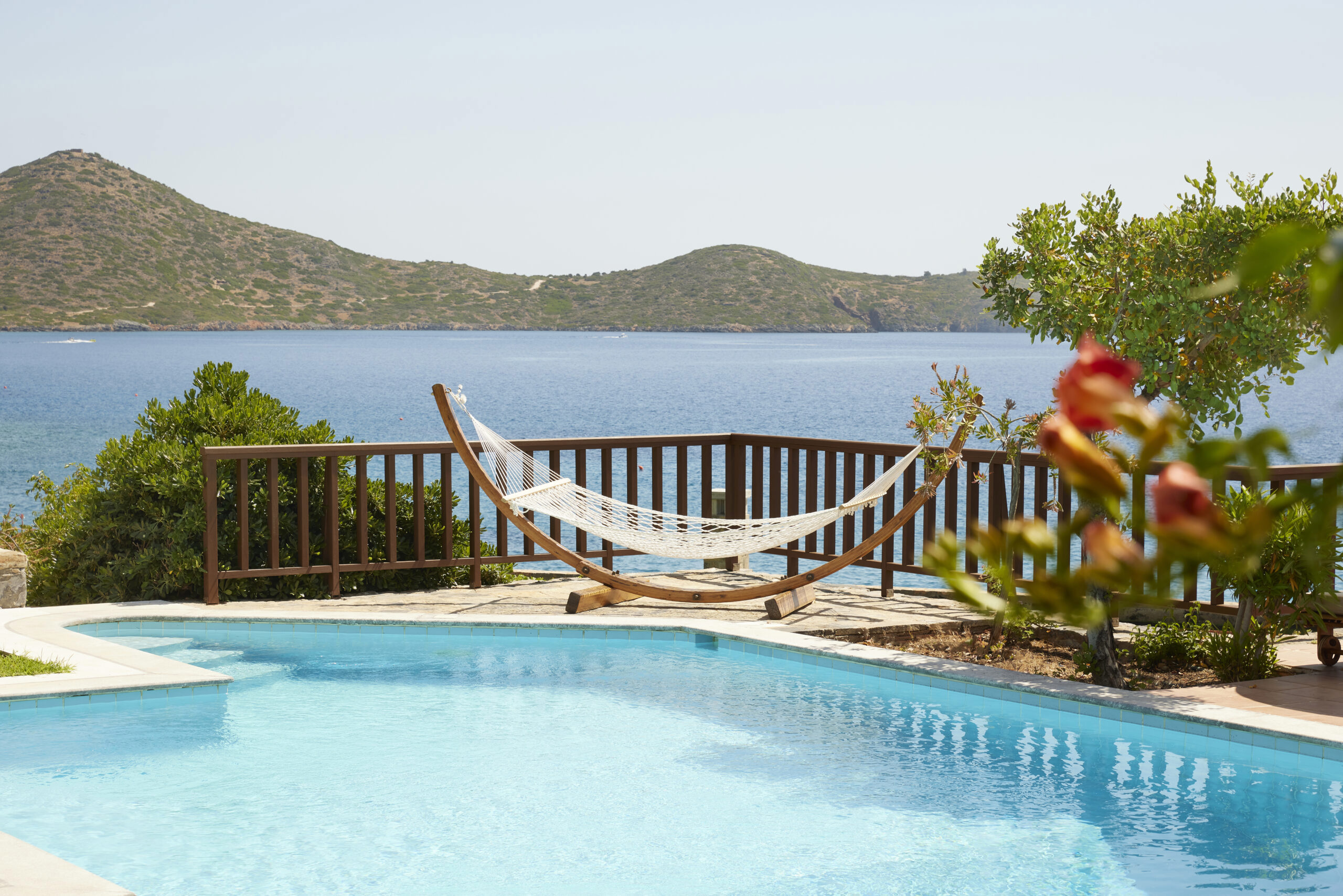 Pool of King Minos room with hammock and sea views surrounded by greenery