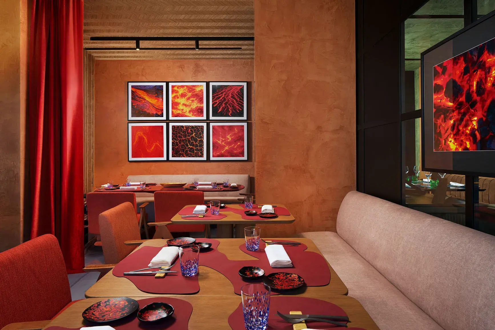 Stylish restaurant interior at Gran Hotel Taoro in Tenerife featuring warm terracotta tones, modern volcanic-themed artwork, and elegantly set dining tables.