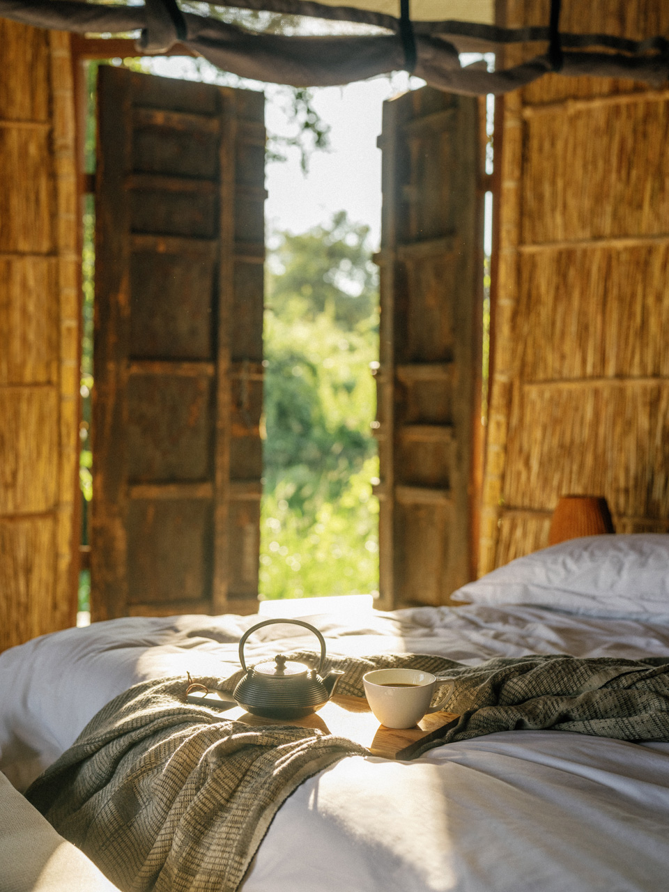 Africa, Zambia, Time + Tide Chinzombo, teapot and mug on a bed in a bedroom