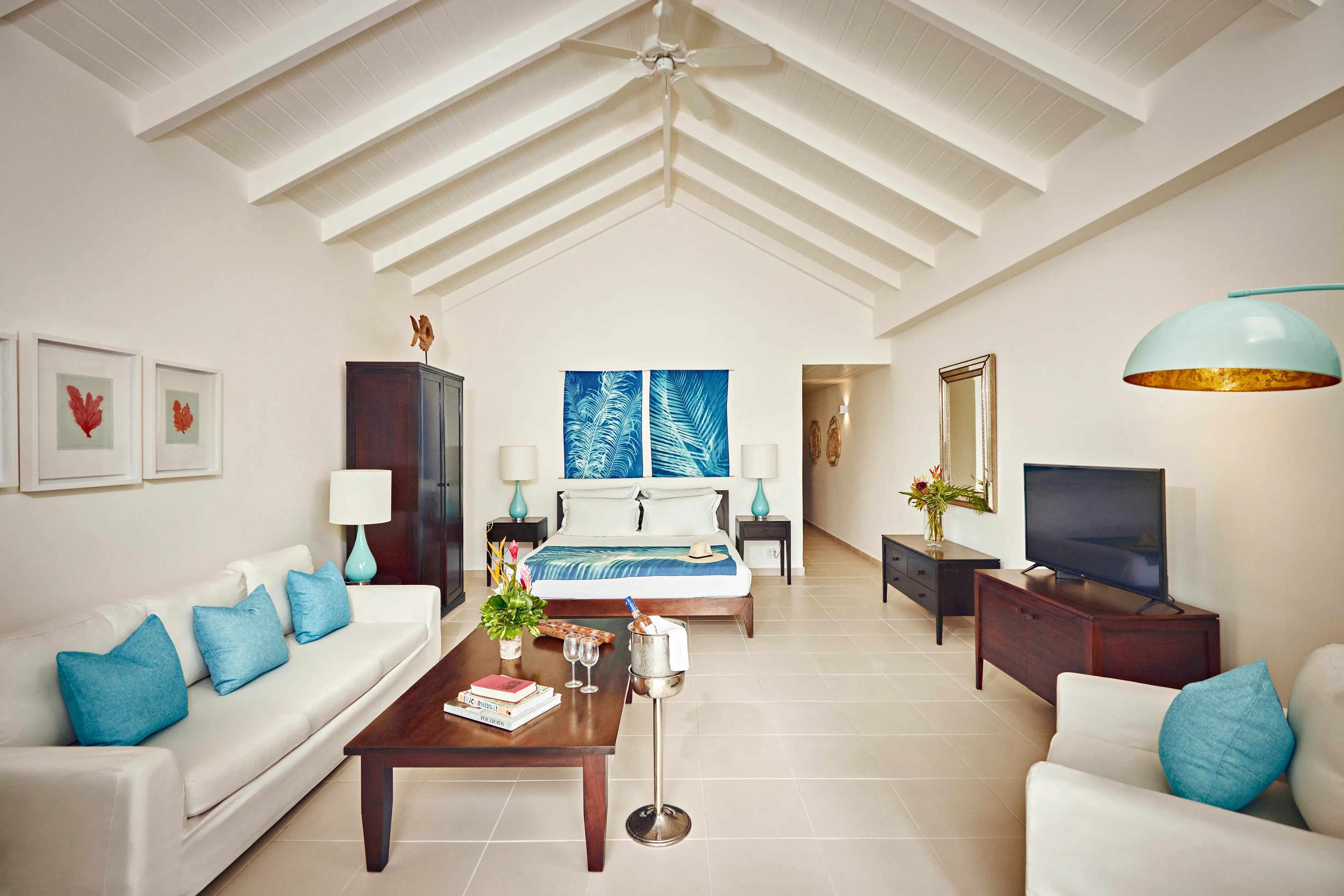 A Beach Balcony Suite at Carlisle Bay in Antigua with high vaulted ceiling and white decor with blue and wooden accents