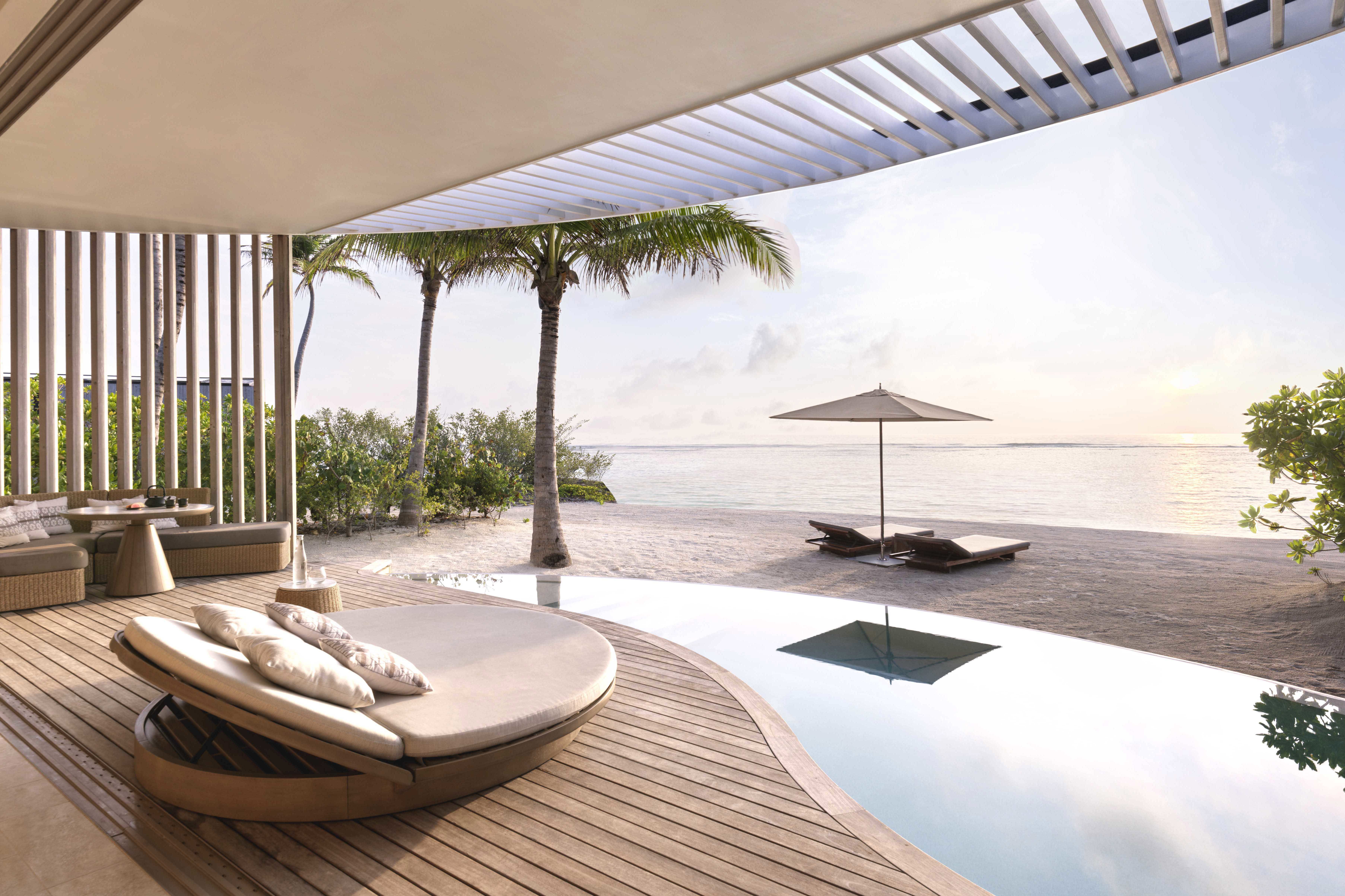 Sun lounger and private pool of beach villa with sun rising over the horizon