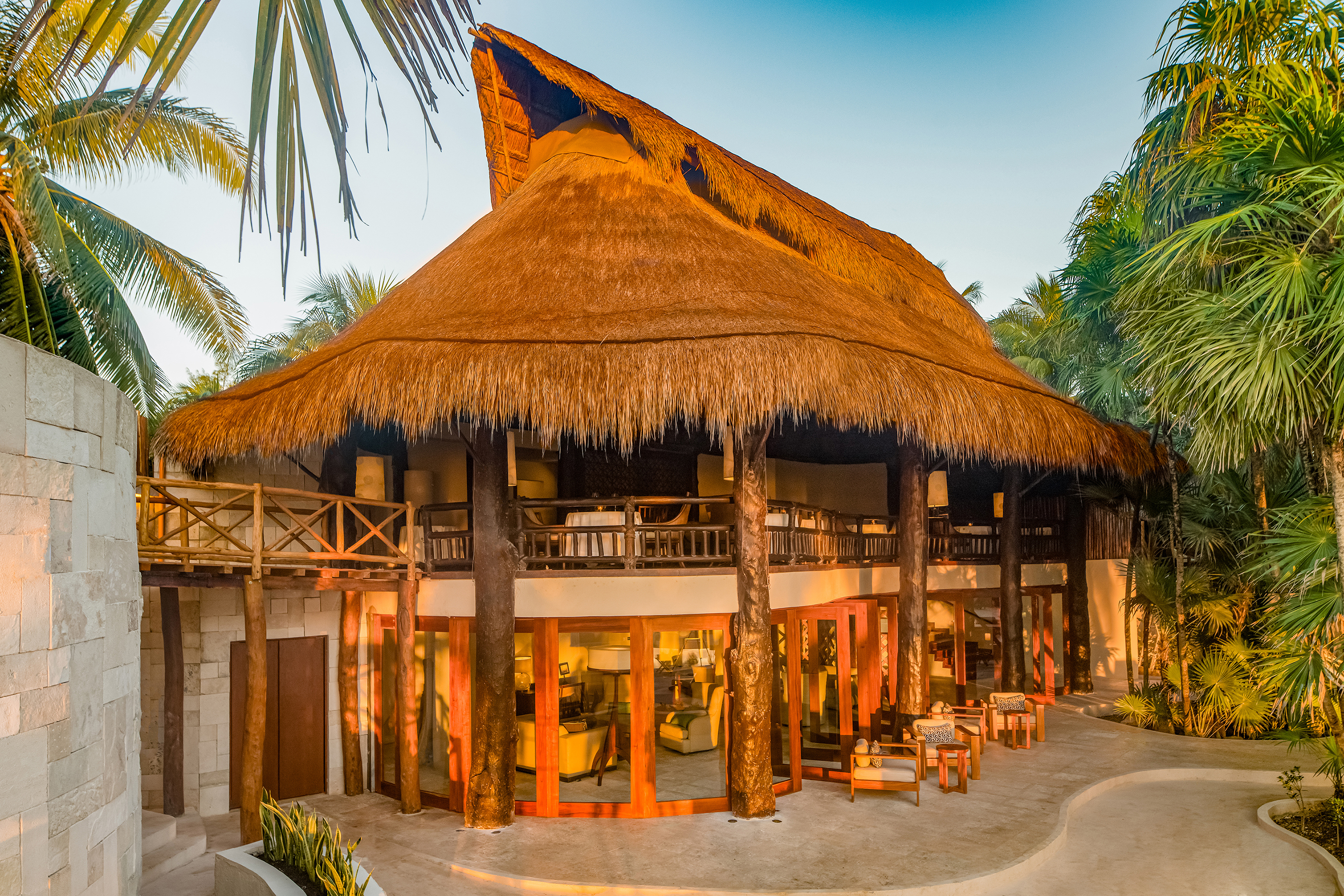 A large thatched building with wooden column bathed in sunset light