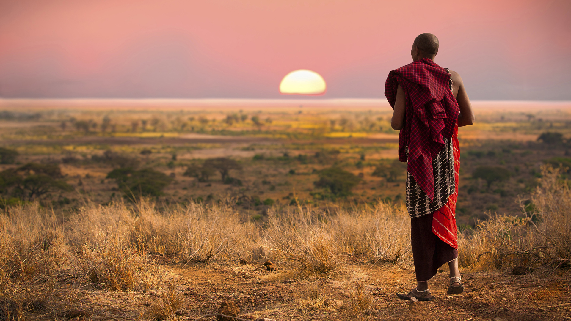 Man in traditional dress in front of sunset 
